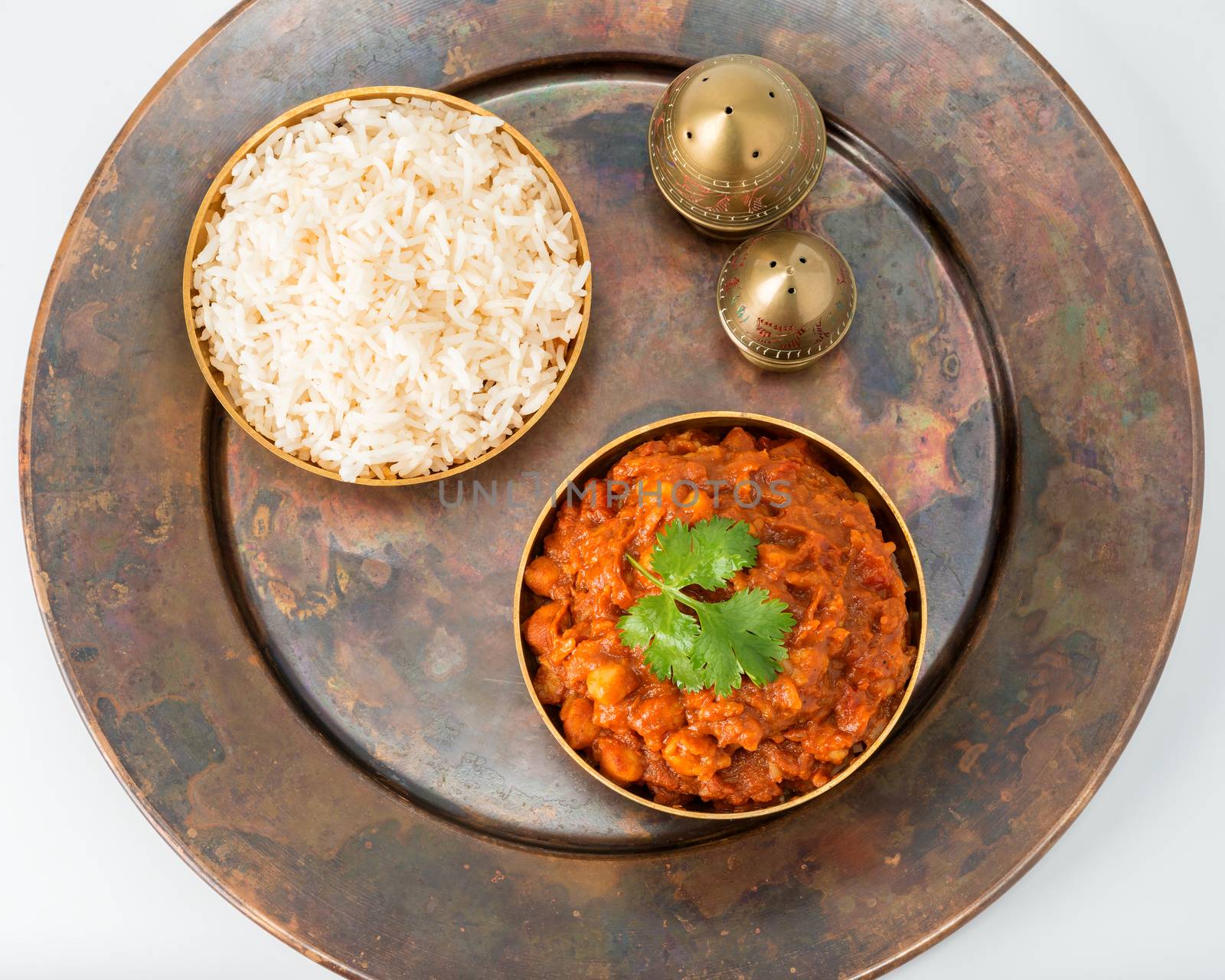 Chana masala on a rustic copper plate photographed from overhead.