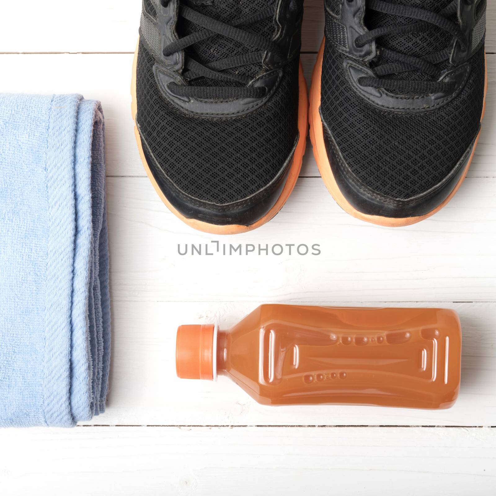 running shoes,towel and orange juice on white wood table