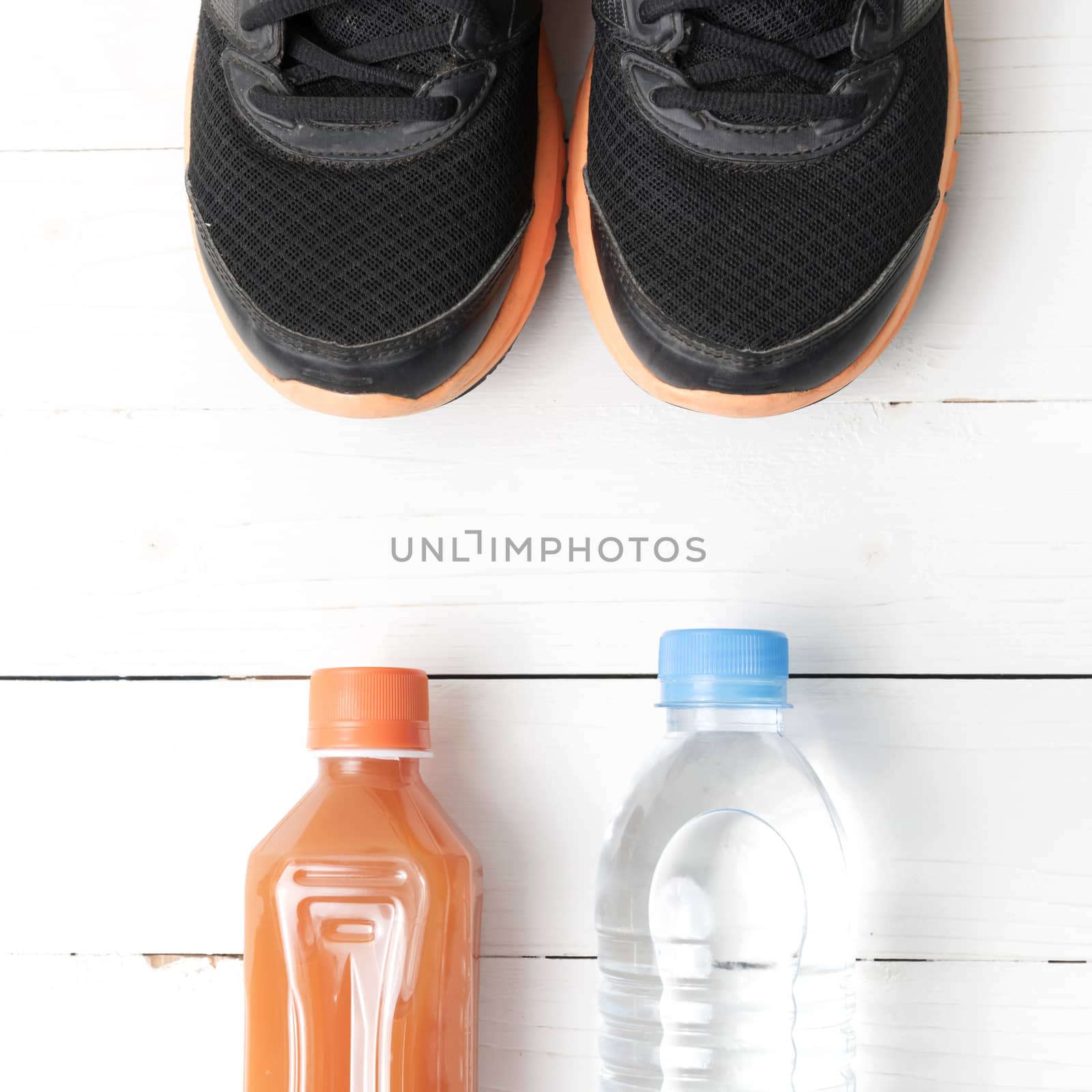 running shoes,drinking water and orange juice on white wood table