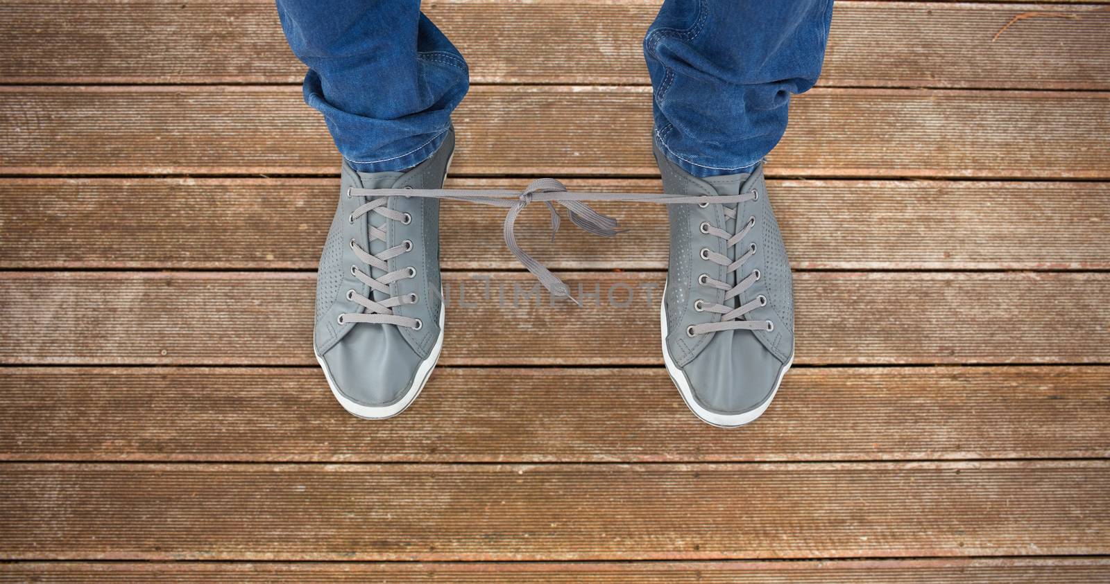 Low section of man with shoelaces tied together  against wooden planks background