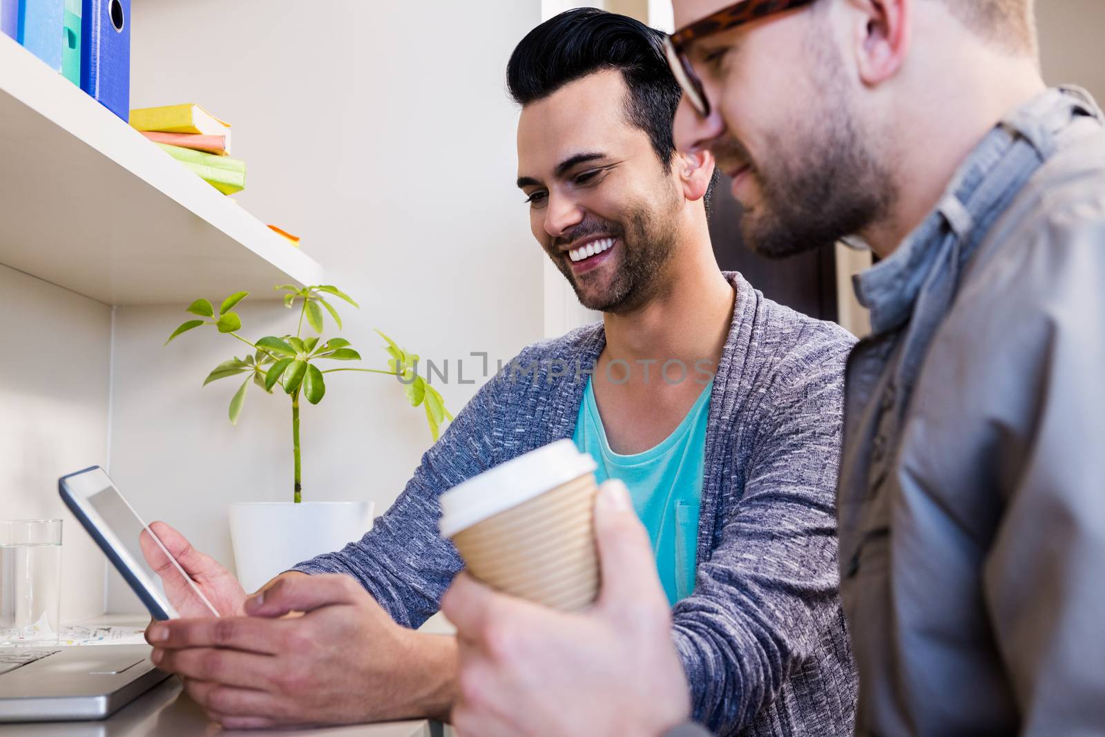 Happy gay couple using tablet at home