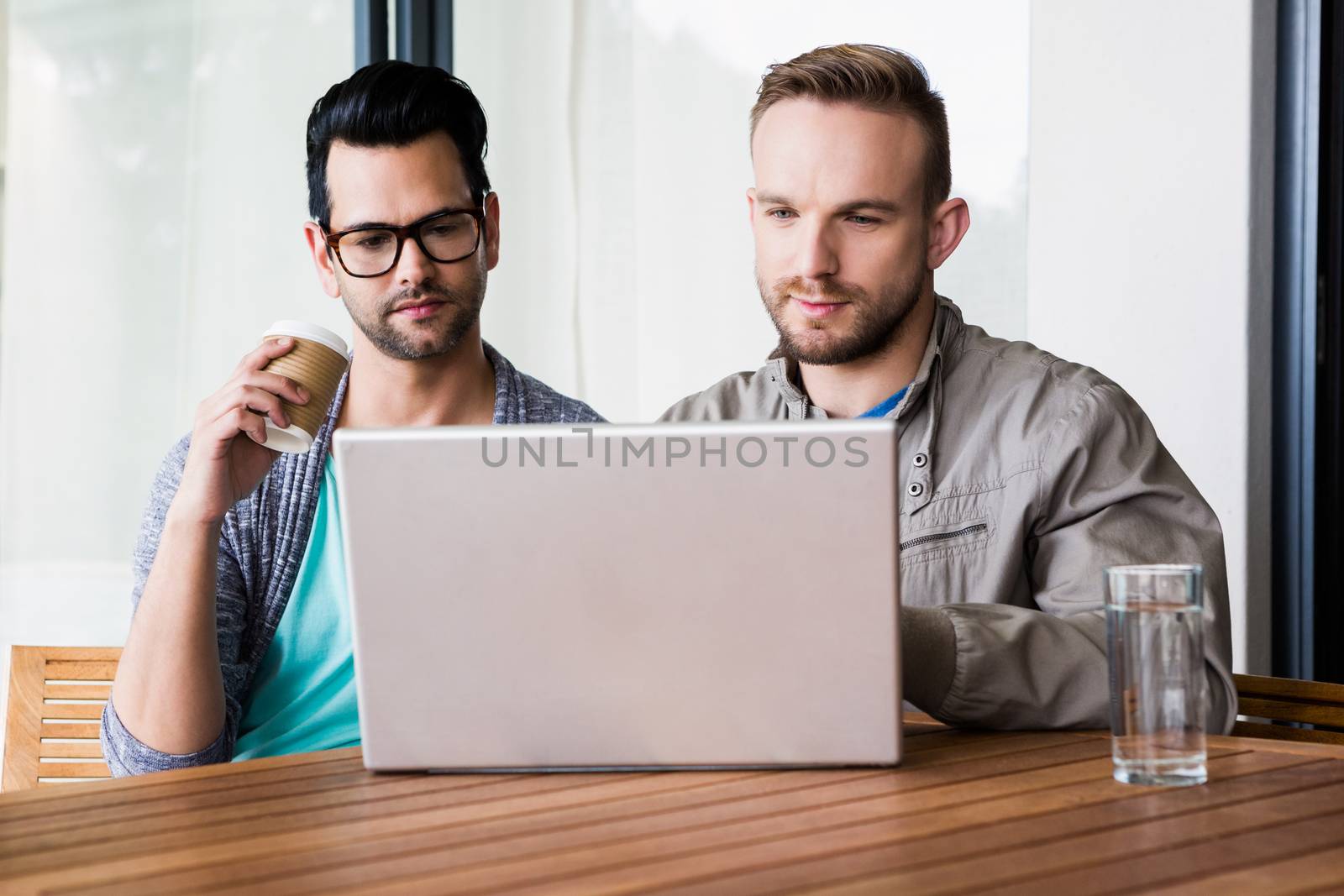 Focused gay couple using laptop outdoors