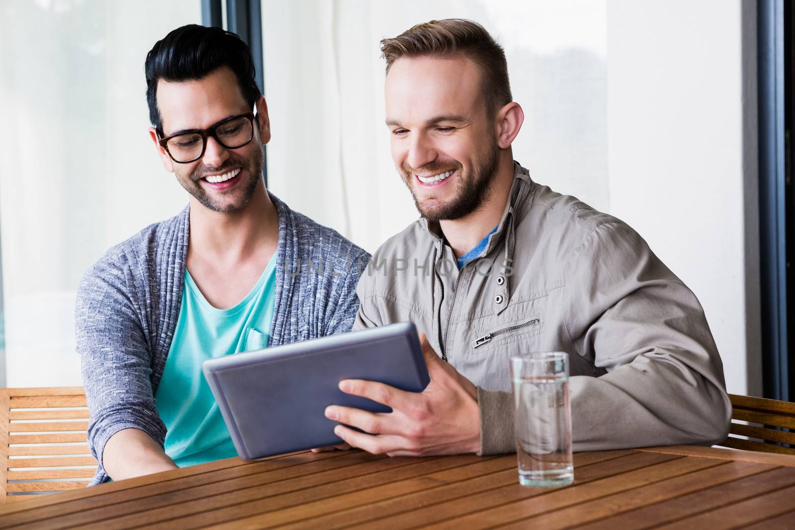 Smiling gay couple using tablet outdoors 