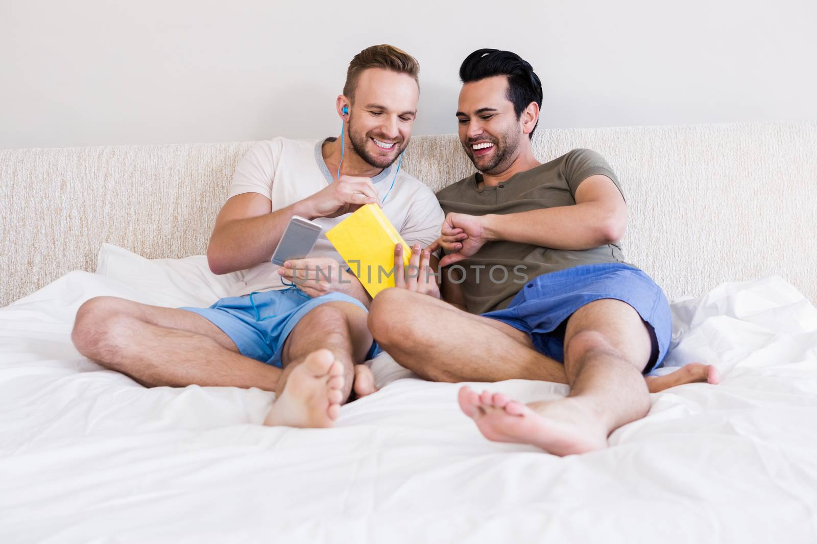 Happy gay couple reading book  by Wavebreakmedia