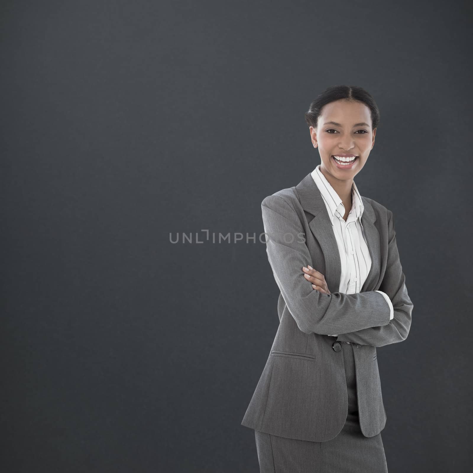 Portrait of smiling businesswoman standing arms crossed against grey background