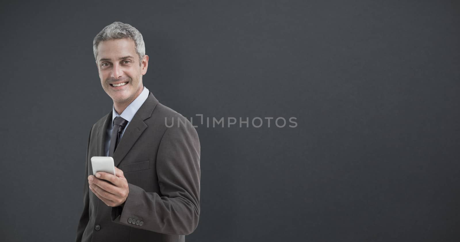 Composite image of portrait of smiling businessman holding mobile phone by Wavebreakmedia