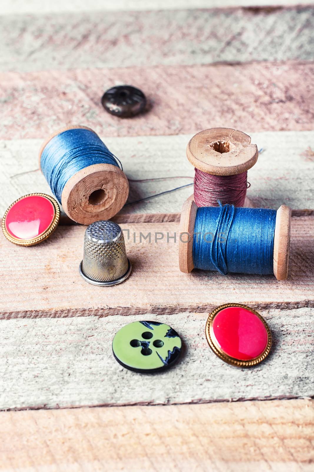 spools of thread and various buttons on wooden background