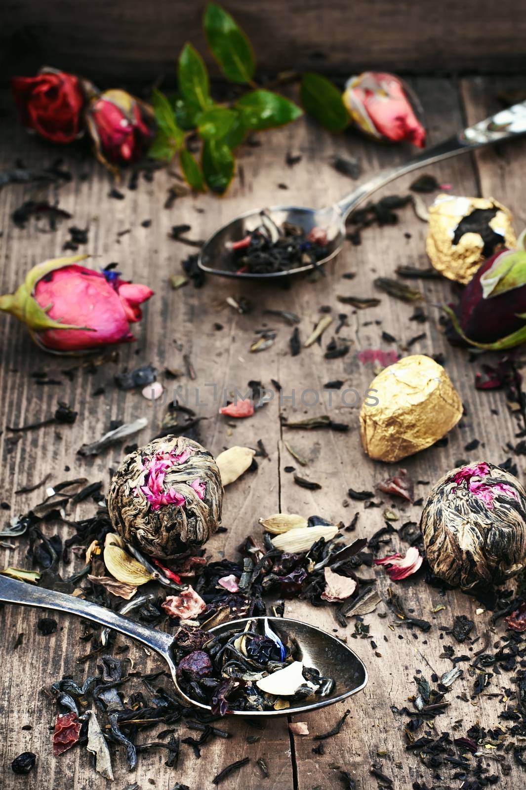 Spoon and spilling the tea leaves of different varieties on retro background