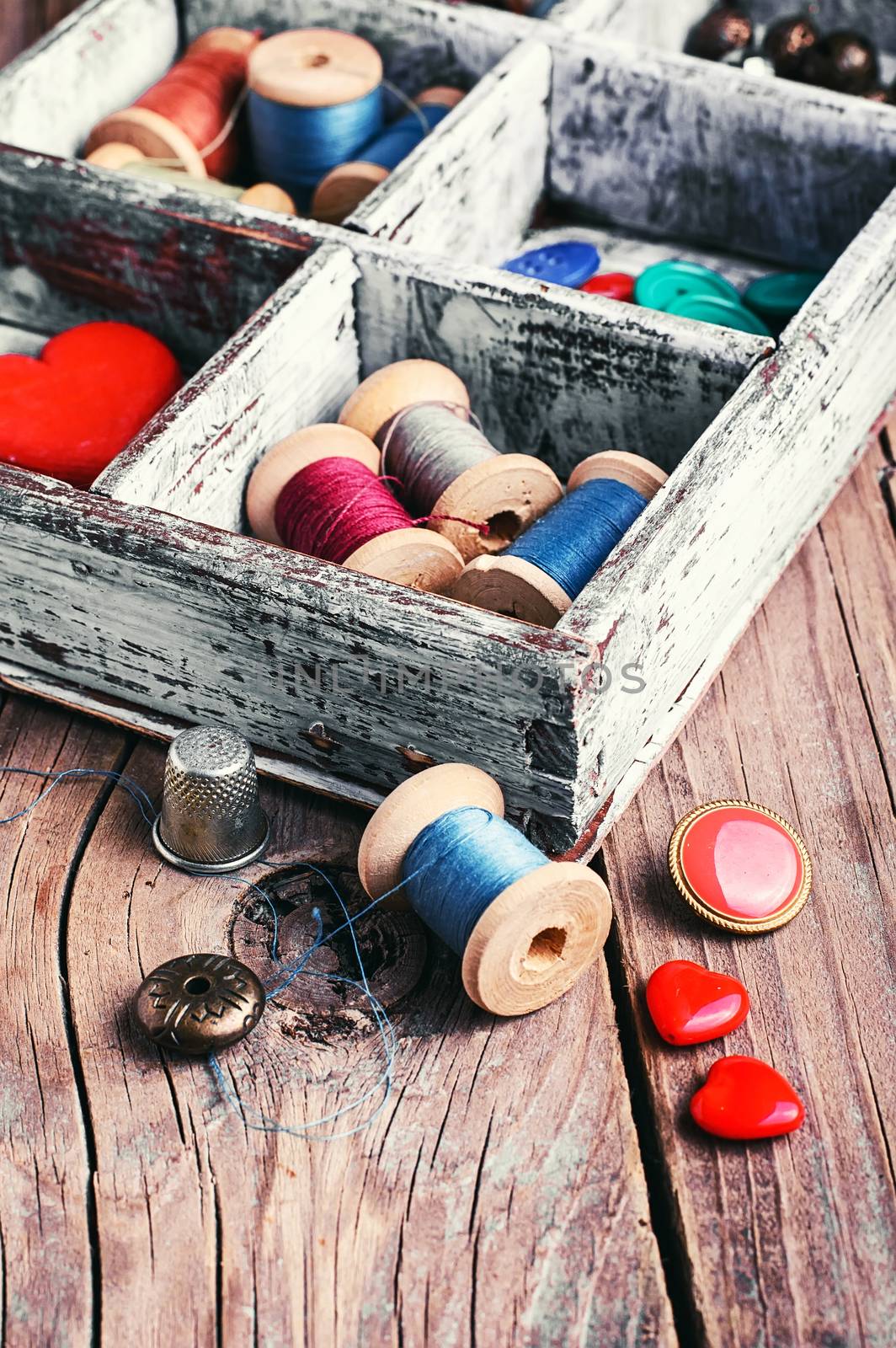 Wooden box with reels of sewing threads and buttons