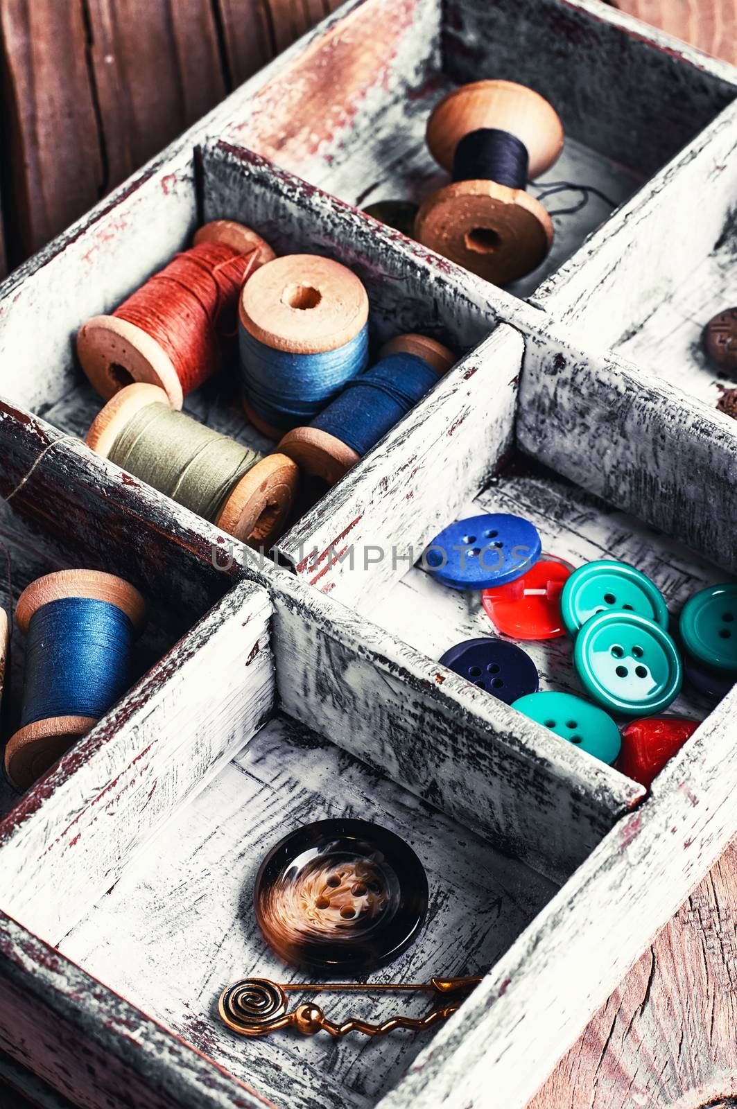 Wooden box with reels of sewing threads and buttons