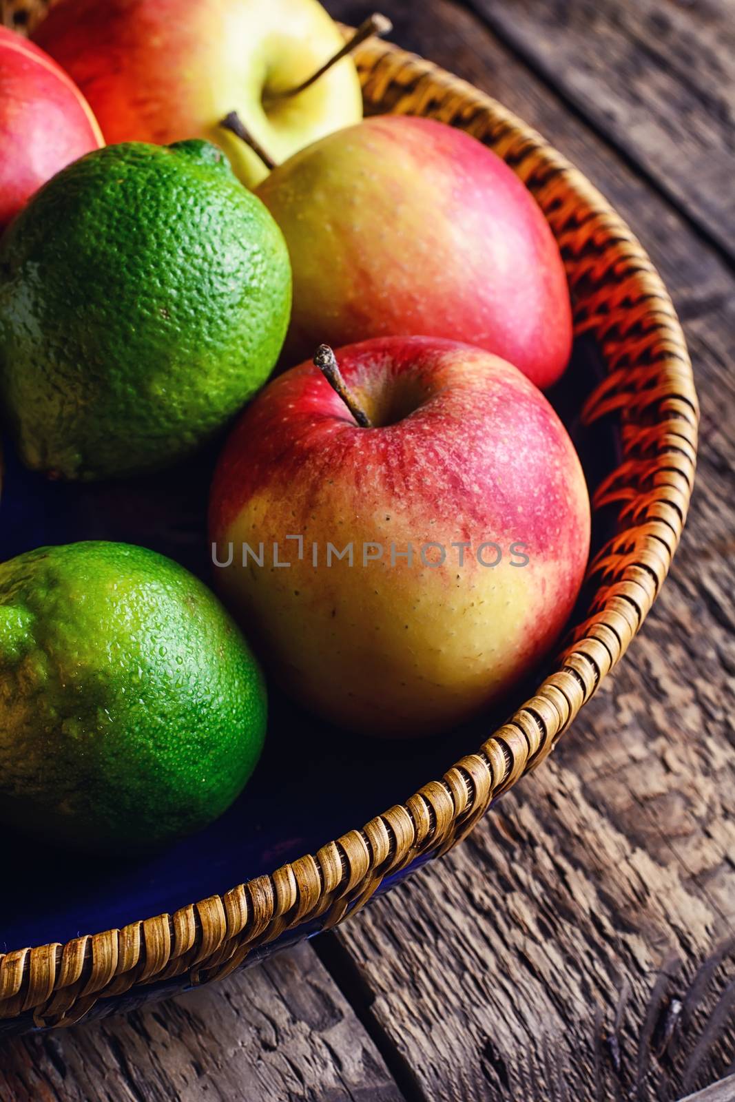 Harvest ripe apples and lime in stylish dish on wooden background