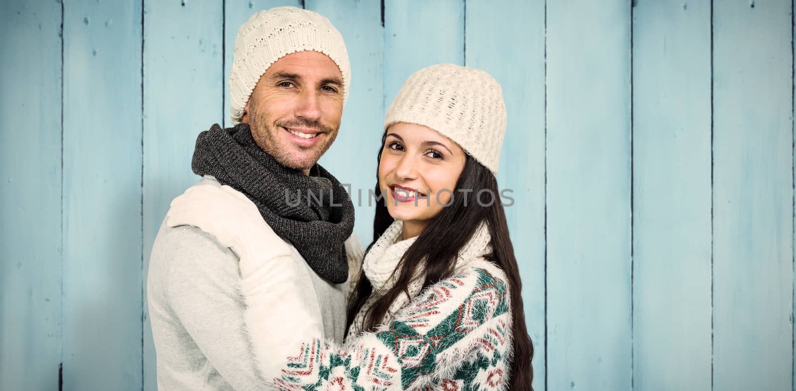 Smiling couple hugging and looking at camera against wooden planks