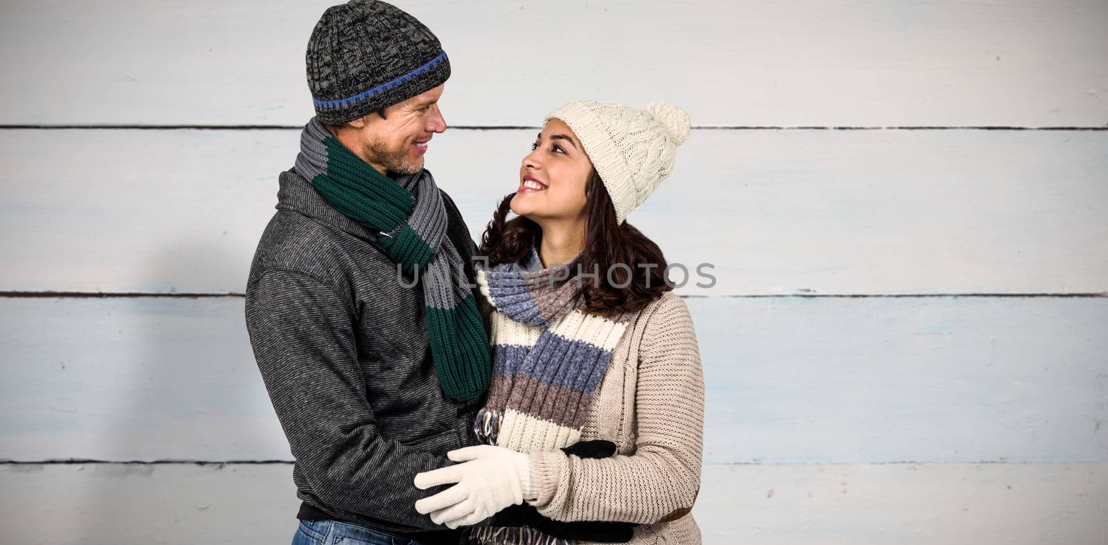 Winter couple enjoying hot drinks against painted blue wooden planks