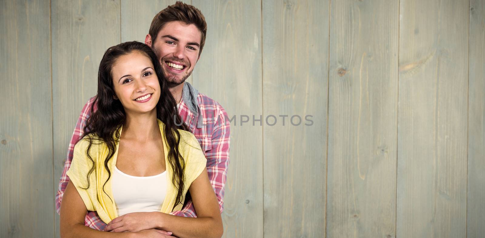 Happy couple hugging and looking at camera against wooden planks