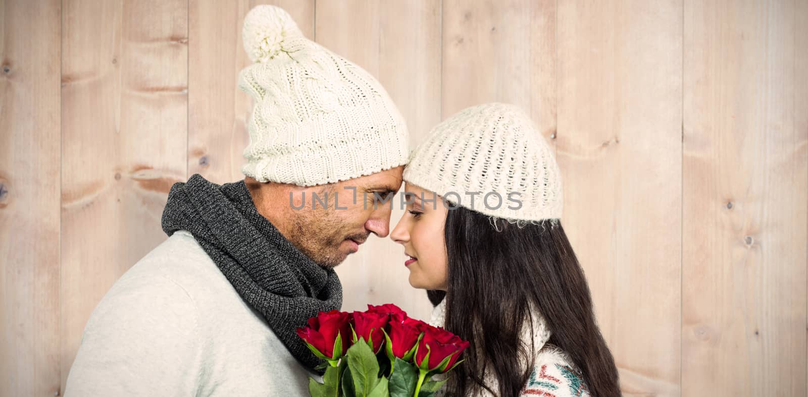 Smiling couple nose-to-nose holding roses bouquet against wooden planks