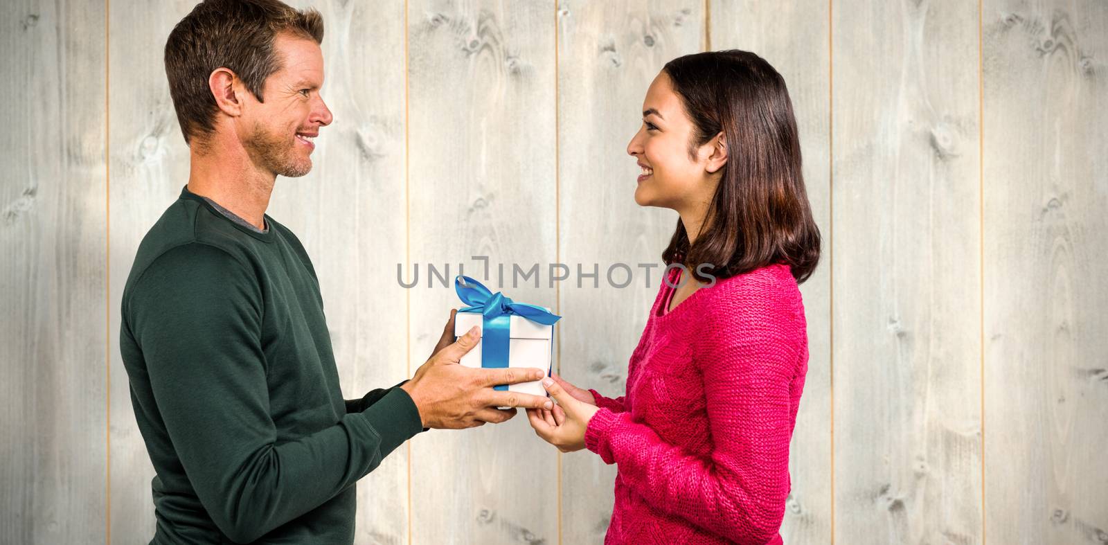 Composite image of smiling couple holding gift box  by Wavebreakmedia