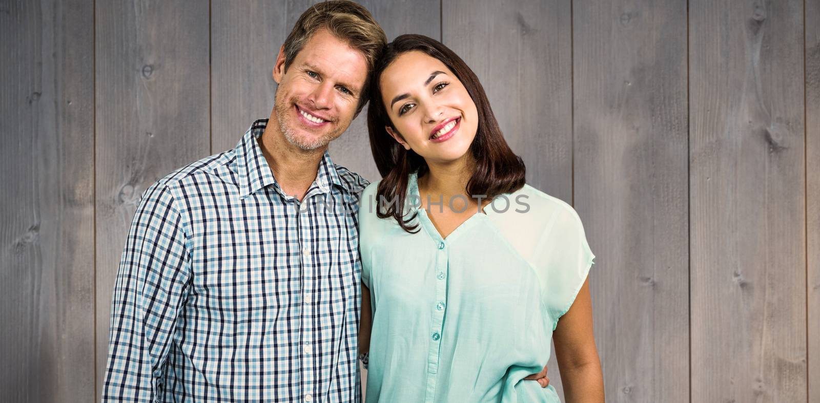 Portrait of happy couple standing against wooden planks