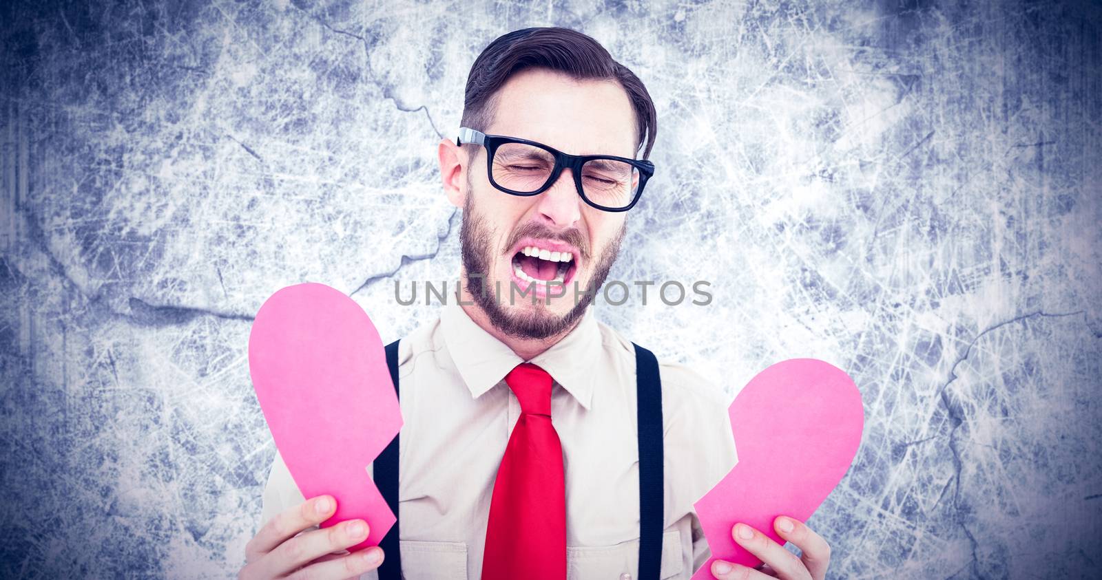 Geeky hipster crying and holding broken heart card against grey background