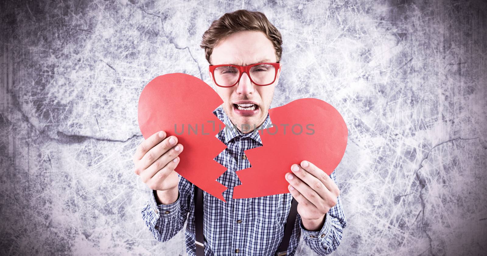 Geeky hipster holding a broken heart  against grey background