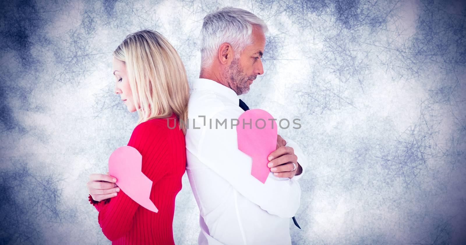 Couple holding two halves of broken heart against grey background