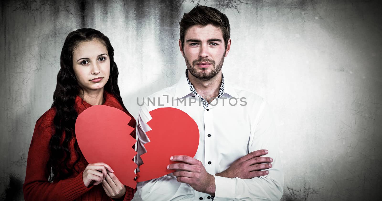 Couple holding heart halves against grey background