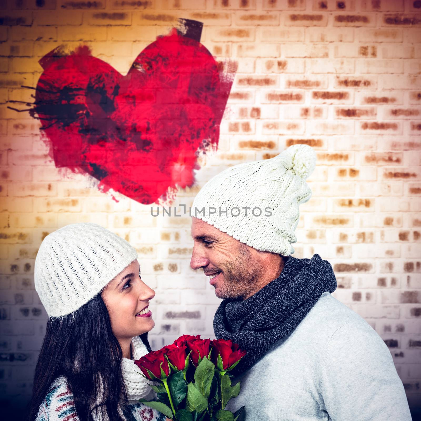 Smiling couple holding roses bouquet against room with orange brick wall