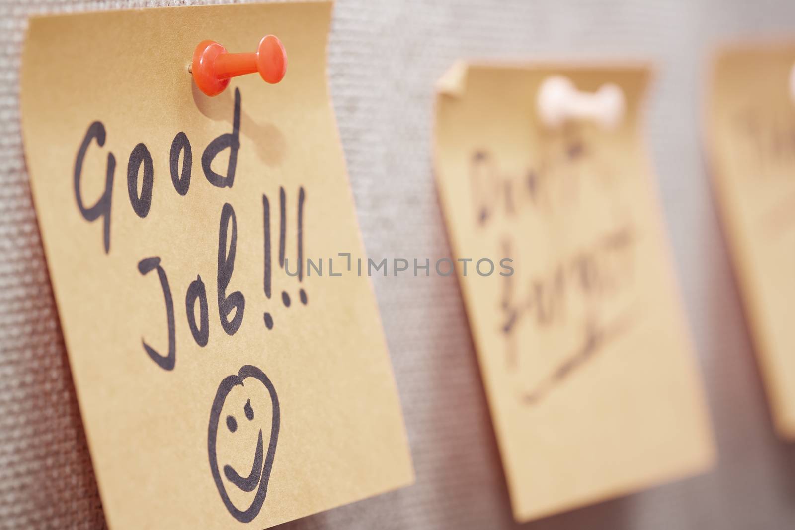 Adhesive note with Good Job text on a cork bulletin board