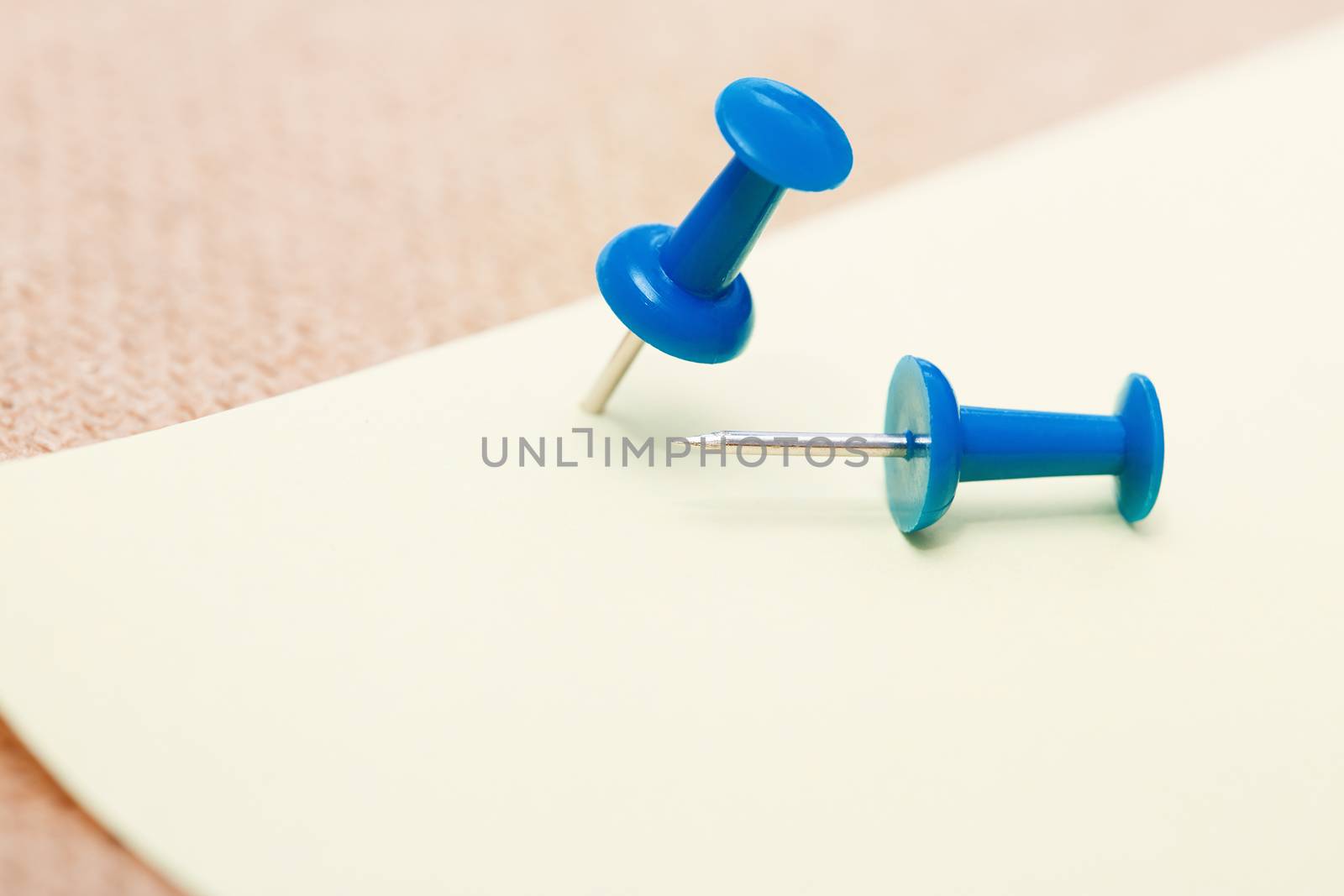 Adhesive note and blue pushpins. Close-up view