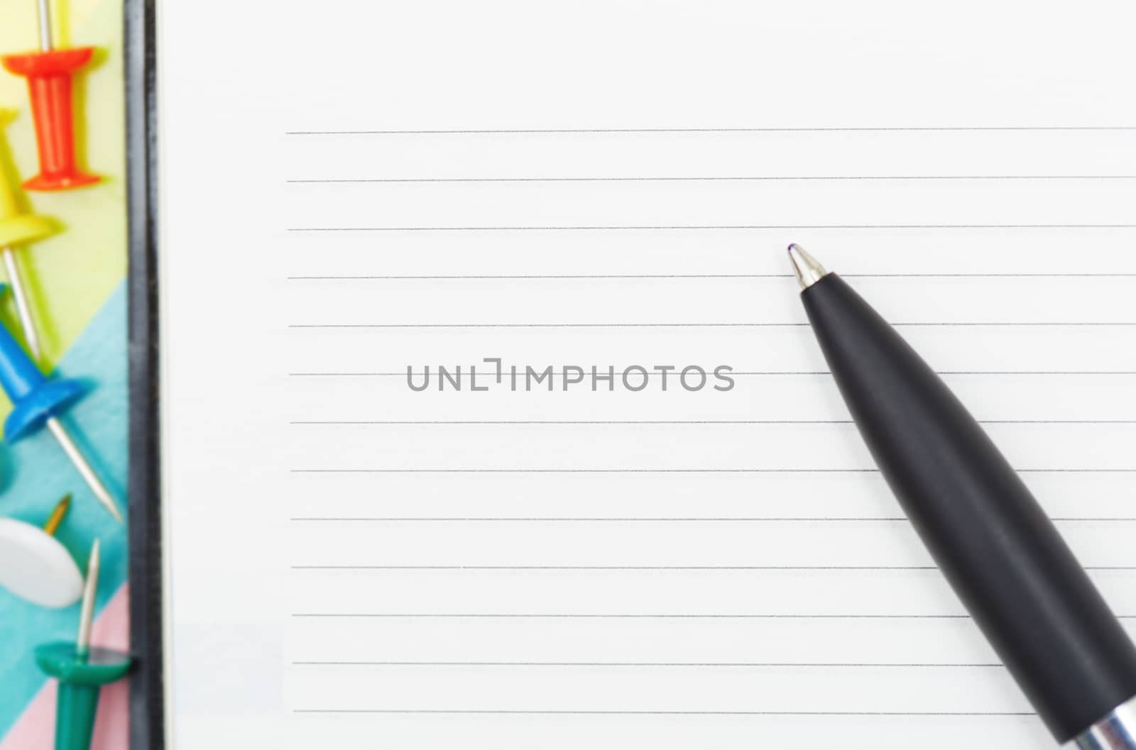 Notepad with pen and pushpins. Close-up photo