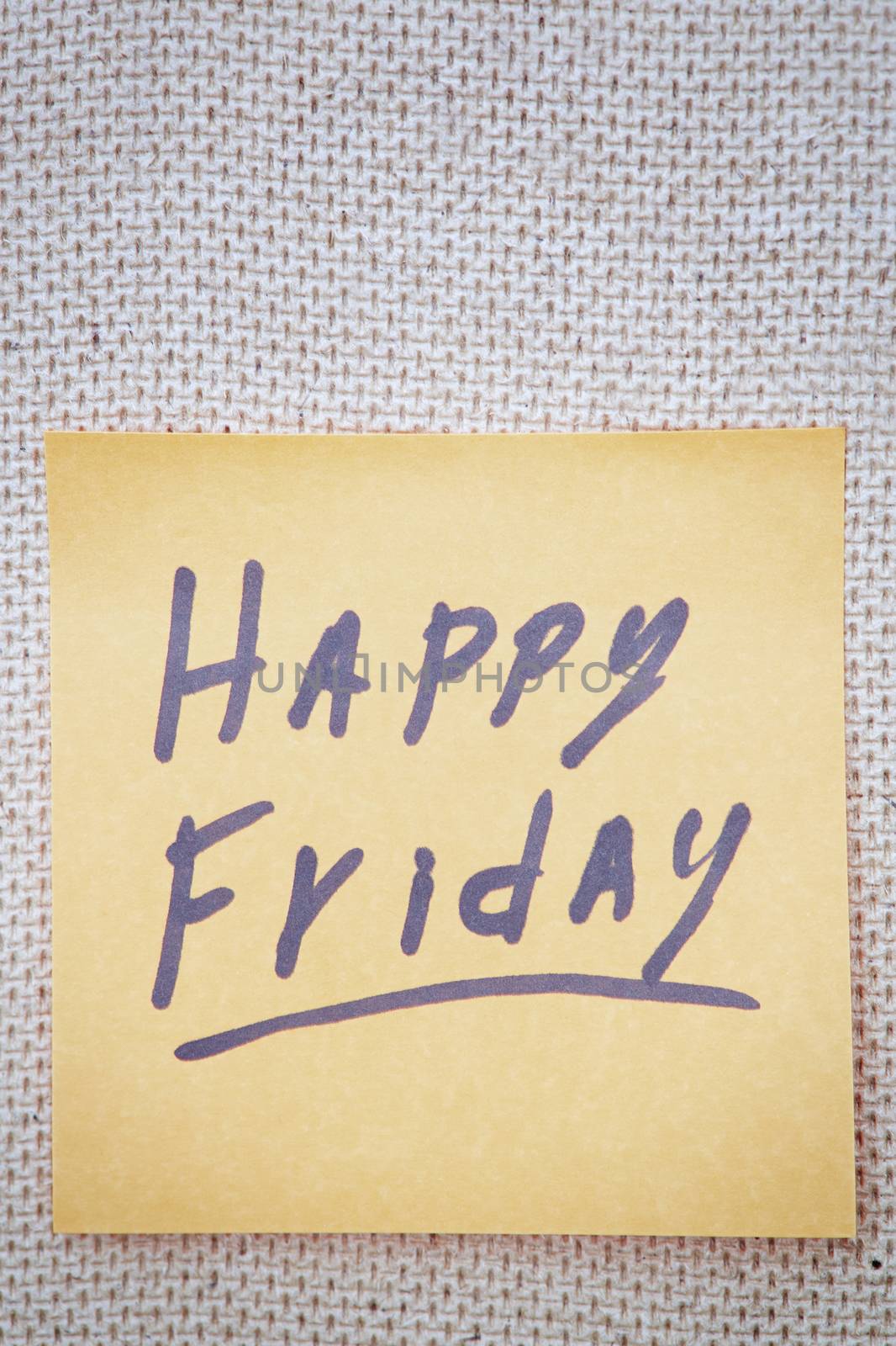 Adhesive note with Happy Friday text on a cork bulletin board