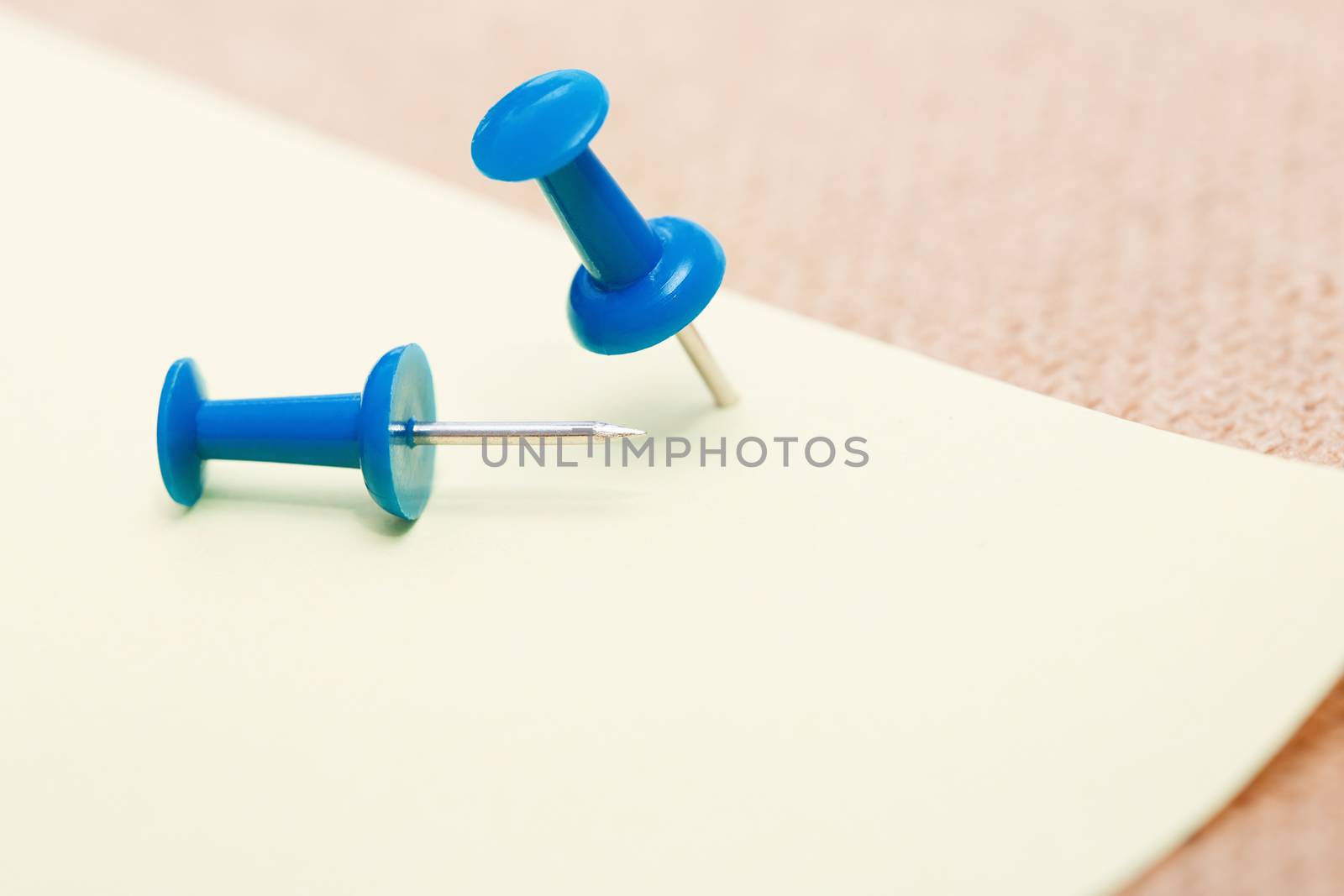 Adhesive note and blue pushpins. Close-up view