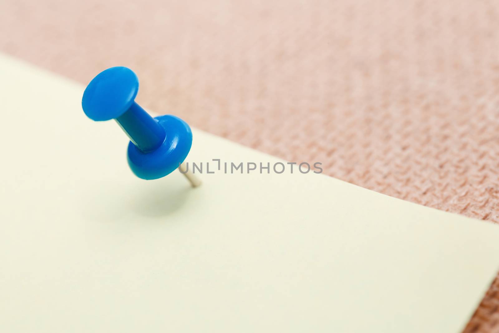 Adhesive note and blue pushpin. Close-up view