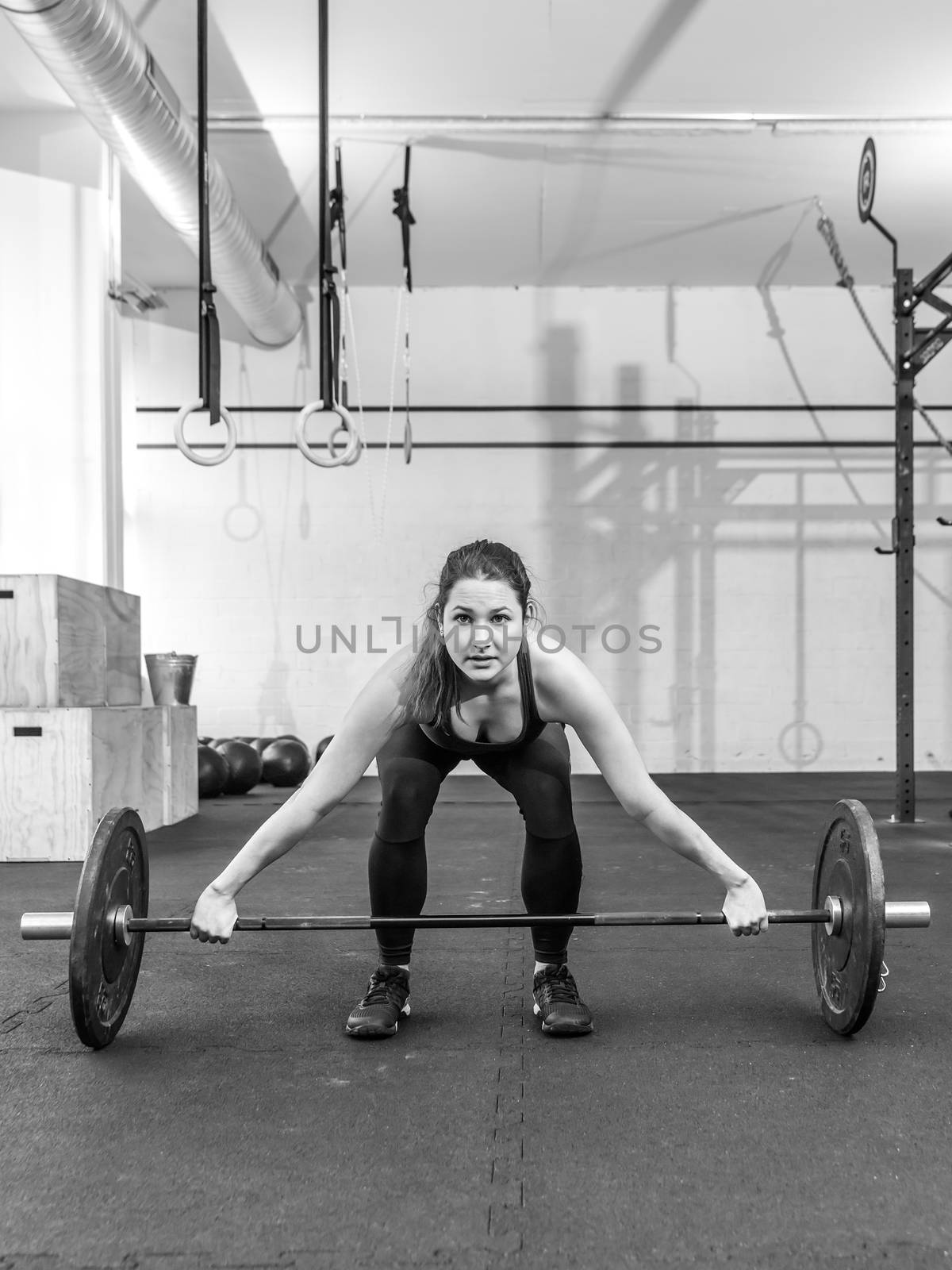 Photo of a young woman at a crossfit gym lifting a barbell.