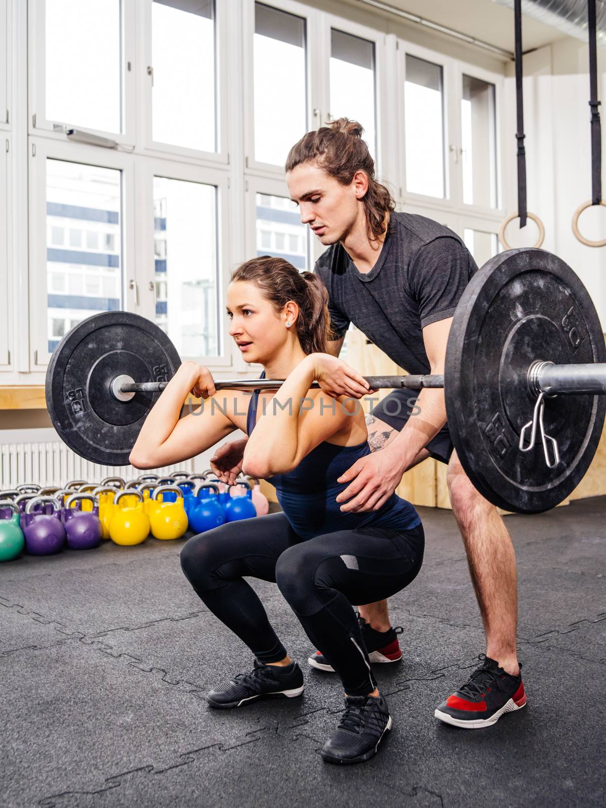 Woman doing squats at crossfit gym by sumners