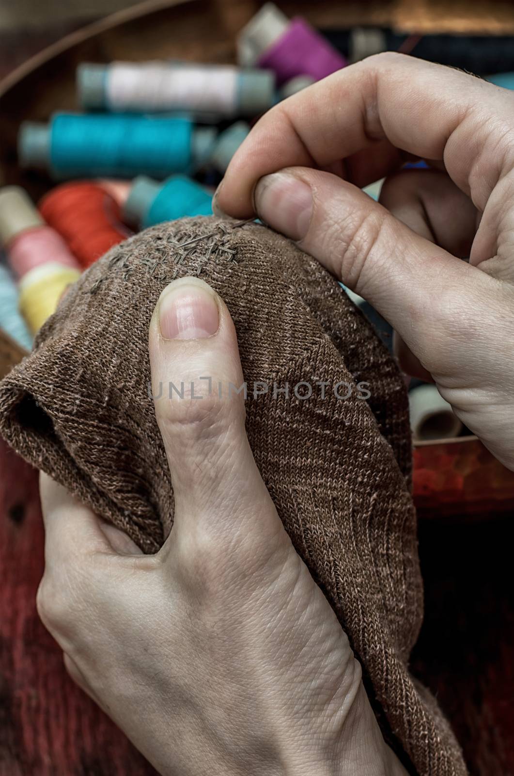 women's hands in the process stepania holey socks on the background of sewing thread