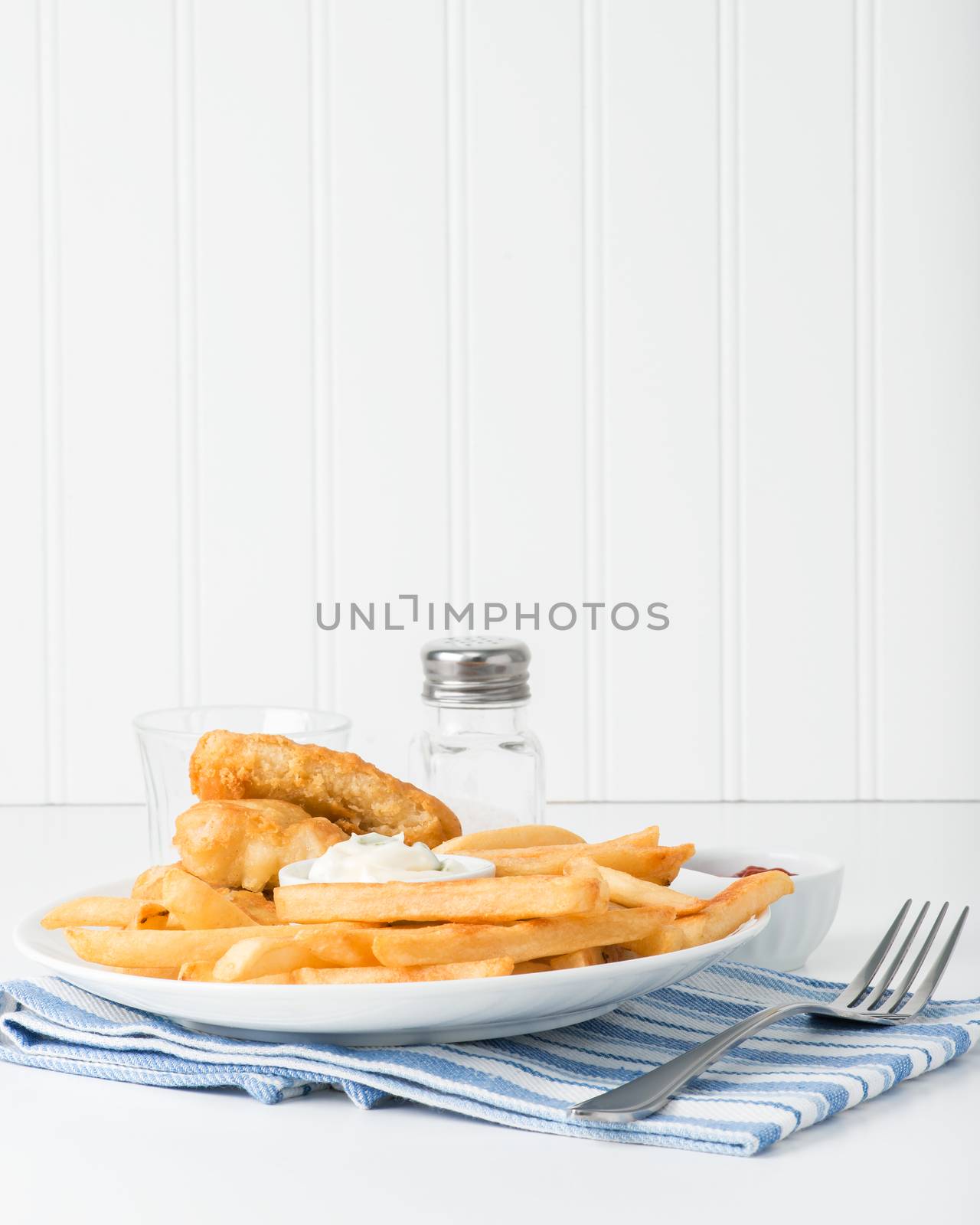 Deep fried potatoes are the main focus of the plate of fish and chips.