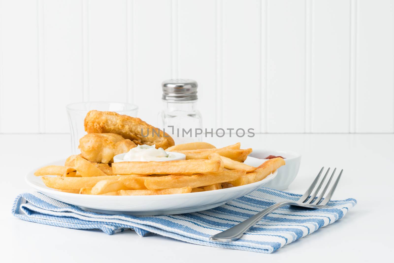 Golden deep fried potatoes with battered fish in the background.