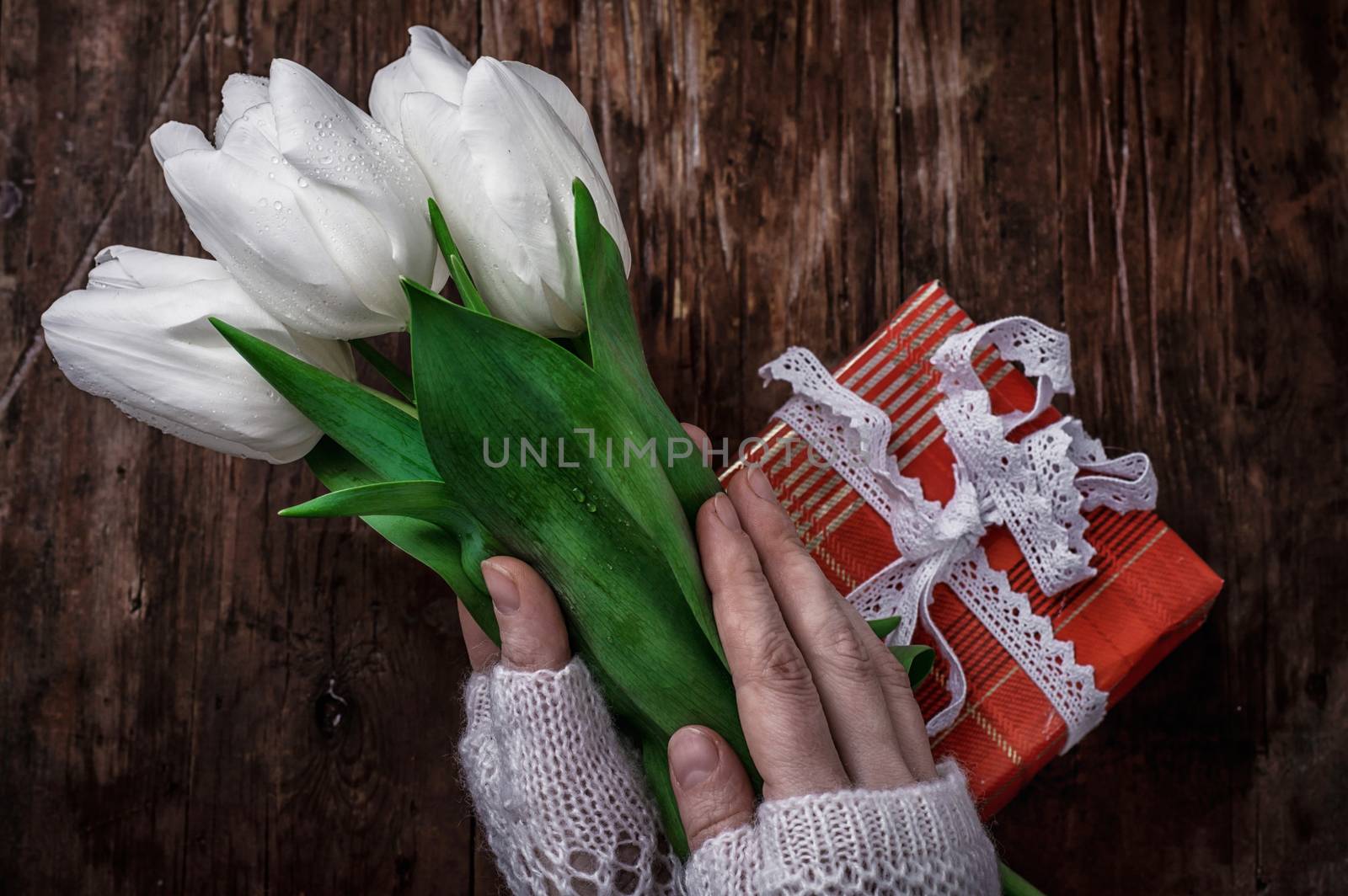 female hand with a bouquet of fresh white tulips