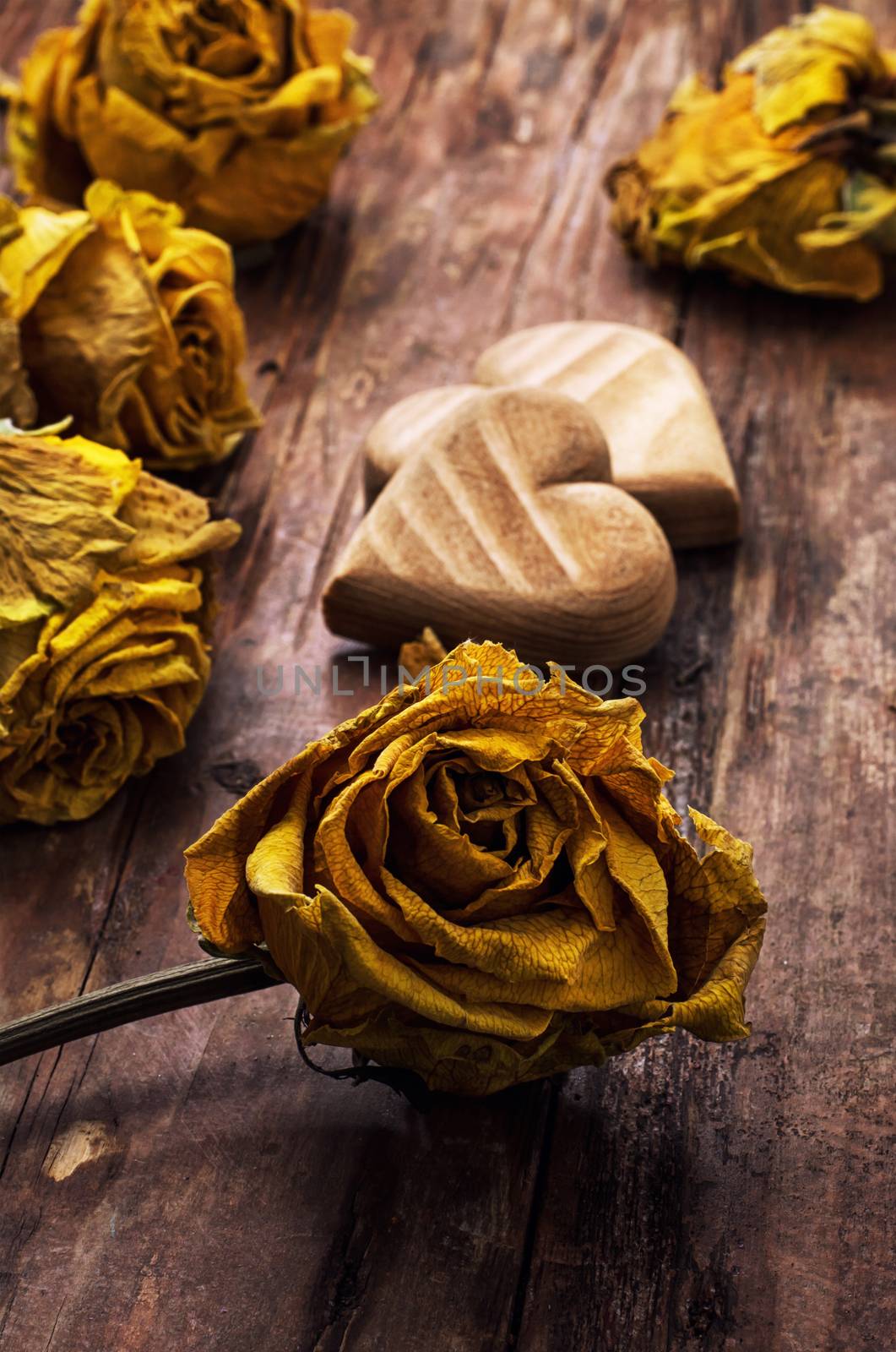 hand-carved symbolic wooden heart on a background of yellow roses