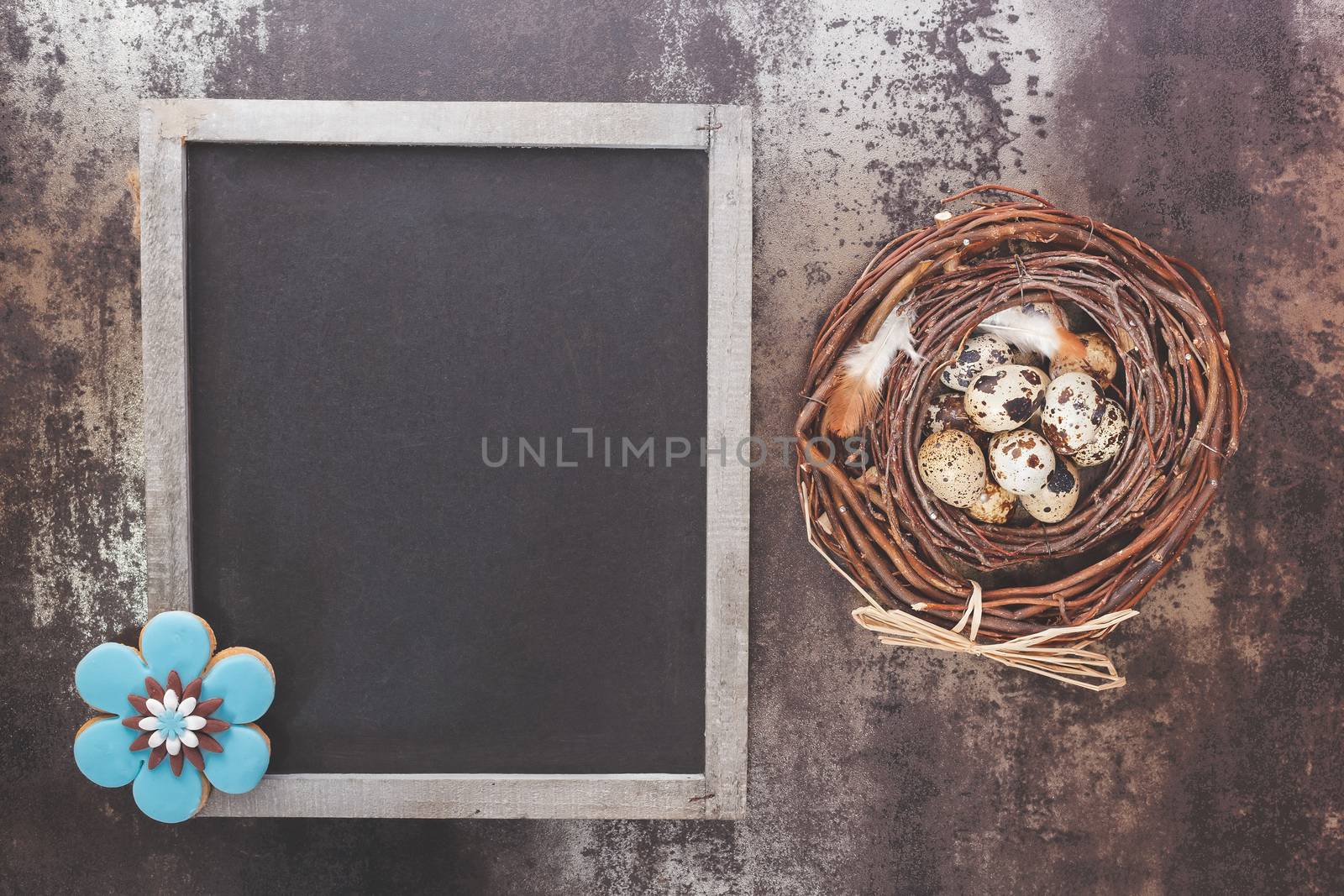 Quail eggs in a nest, blackboard and Easter traditional gingerbread cookie in flower shape. Overhead view with retro style processing, blank space. Natural light