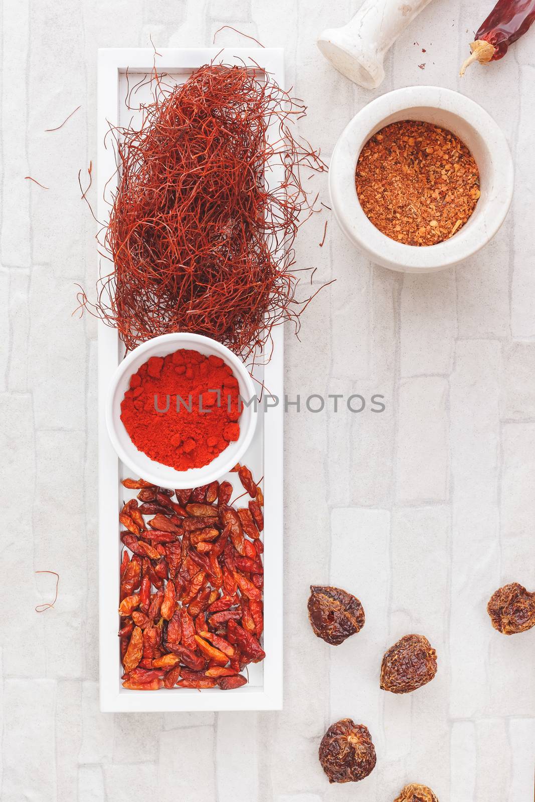 Selection of chili peppers, including: chili powder; crushed red pepper; chili peppers,chili threads and dried chili habanero. Overhead view, blank space. Natural light