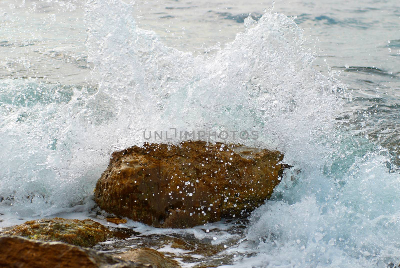 Sea wave covered the rock. Splashes and drops of water