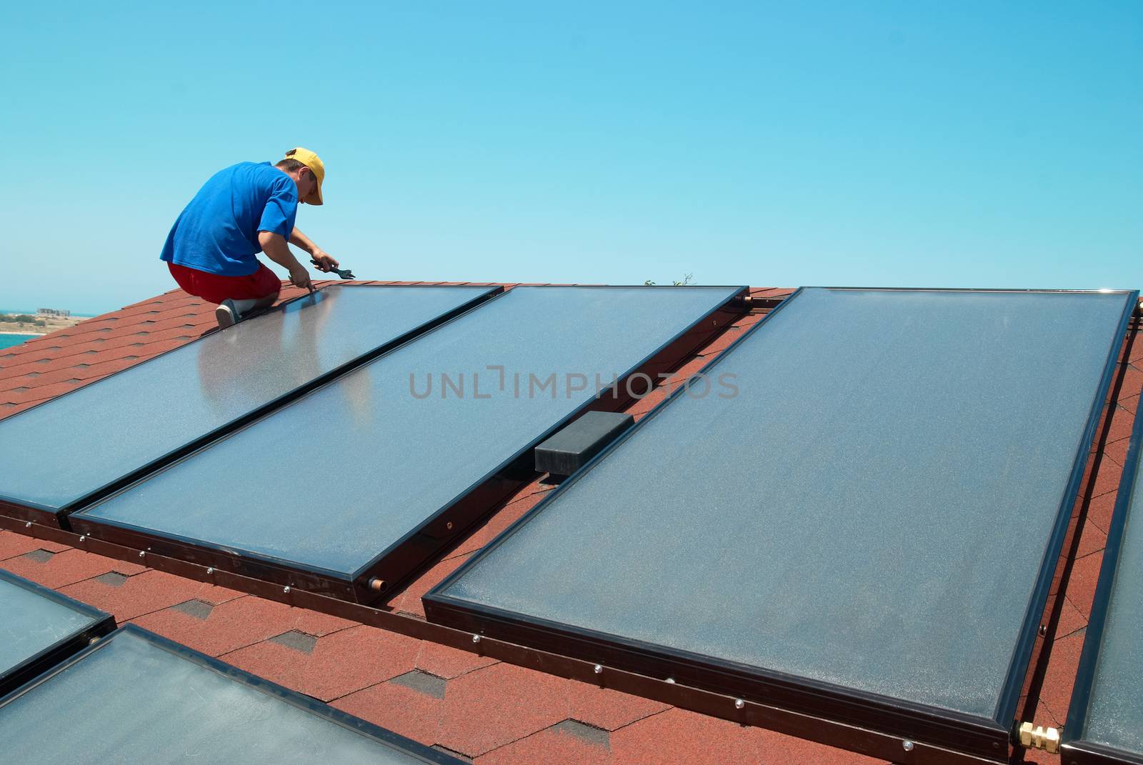 Worker solar water heating panels on the roof.