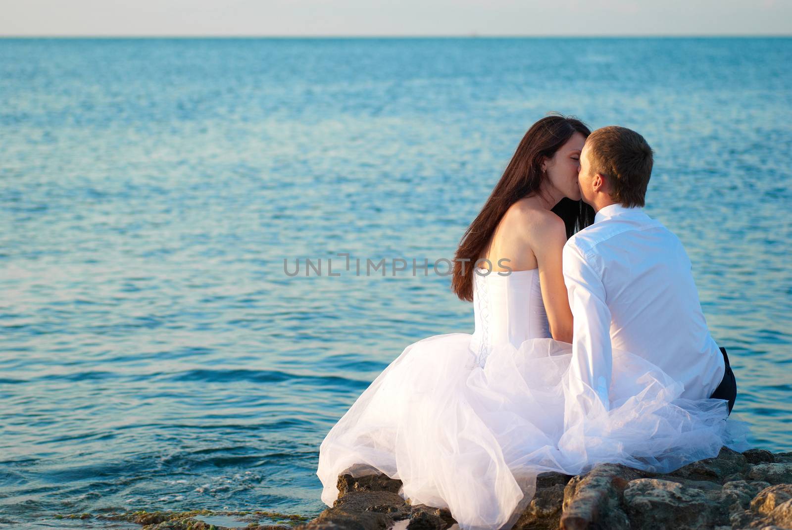 Beautiful wedding couple- bride and groom kissing at the beach. Just married