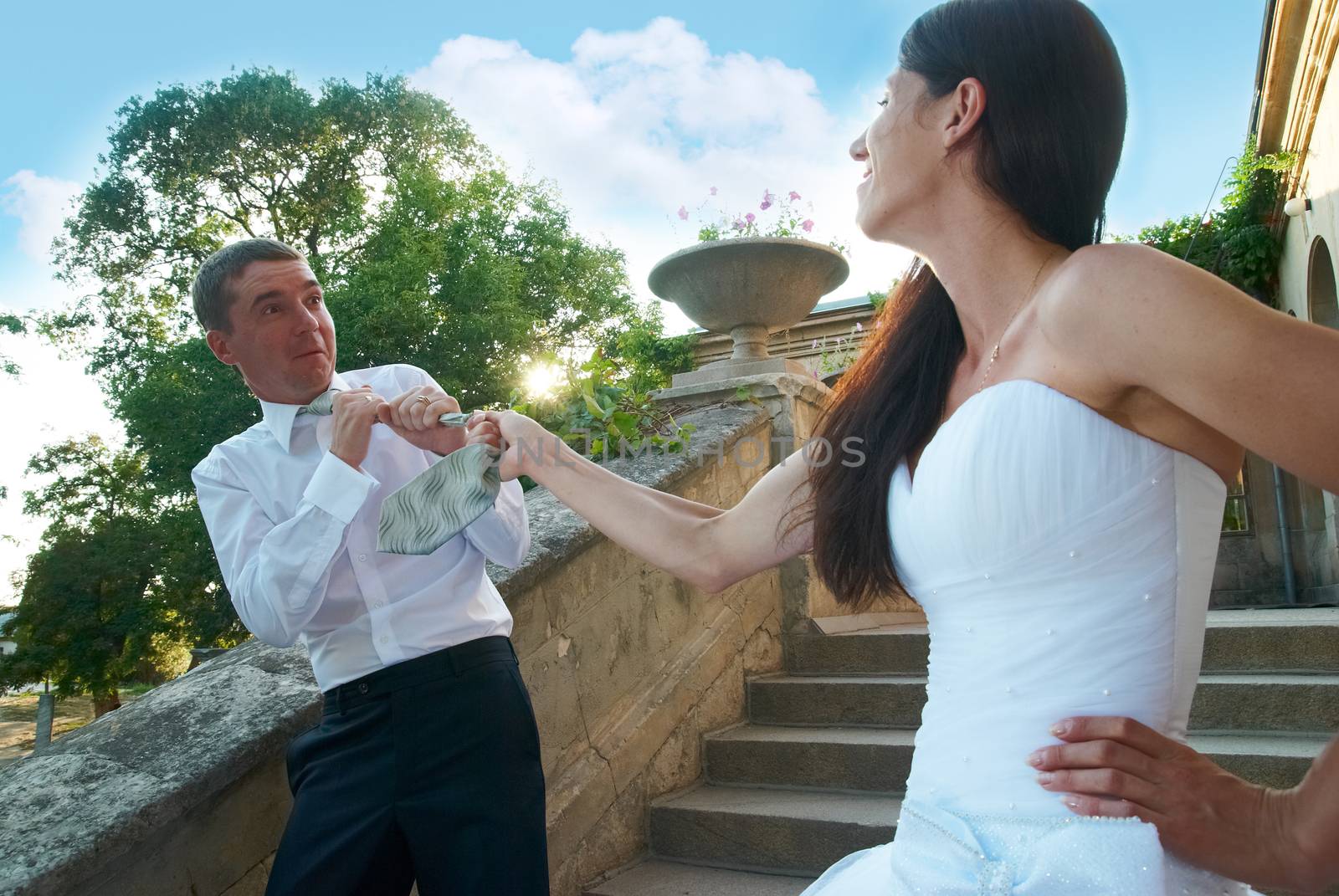 Beautiful wedding couple. Bride pulling groom by the tie