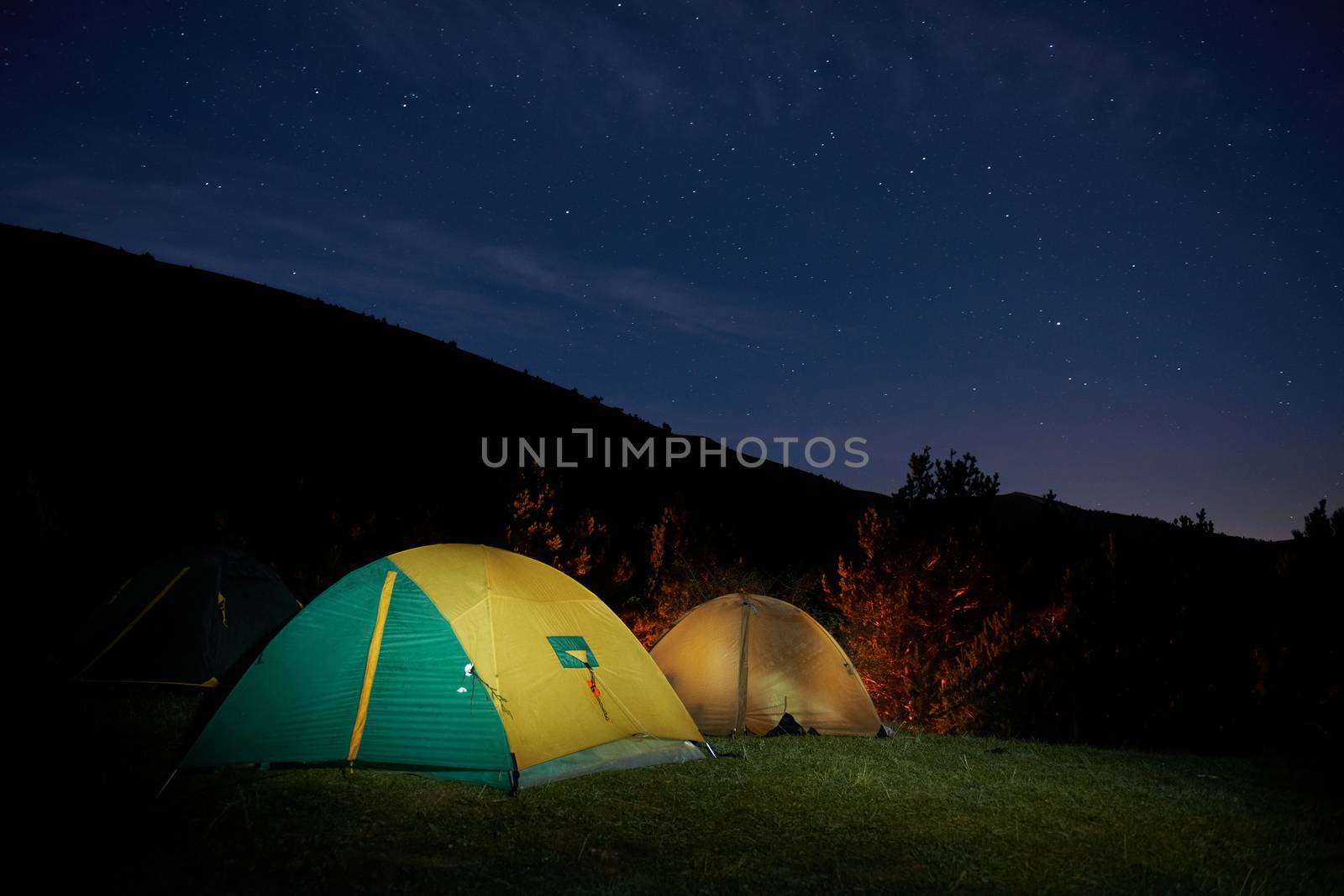 Illuminated yellow camping tent under stars at night