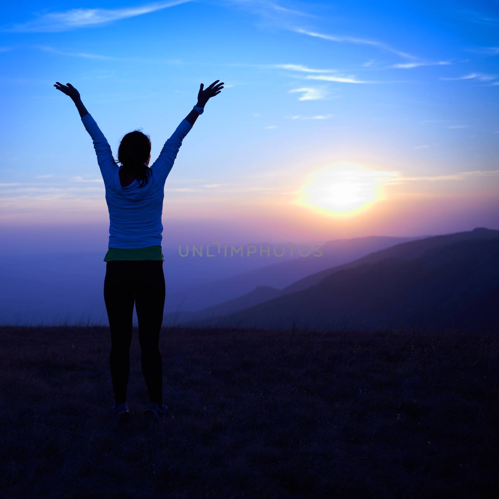 Silhouette of young woman against sunset with blue sky