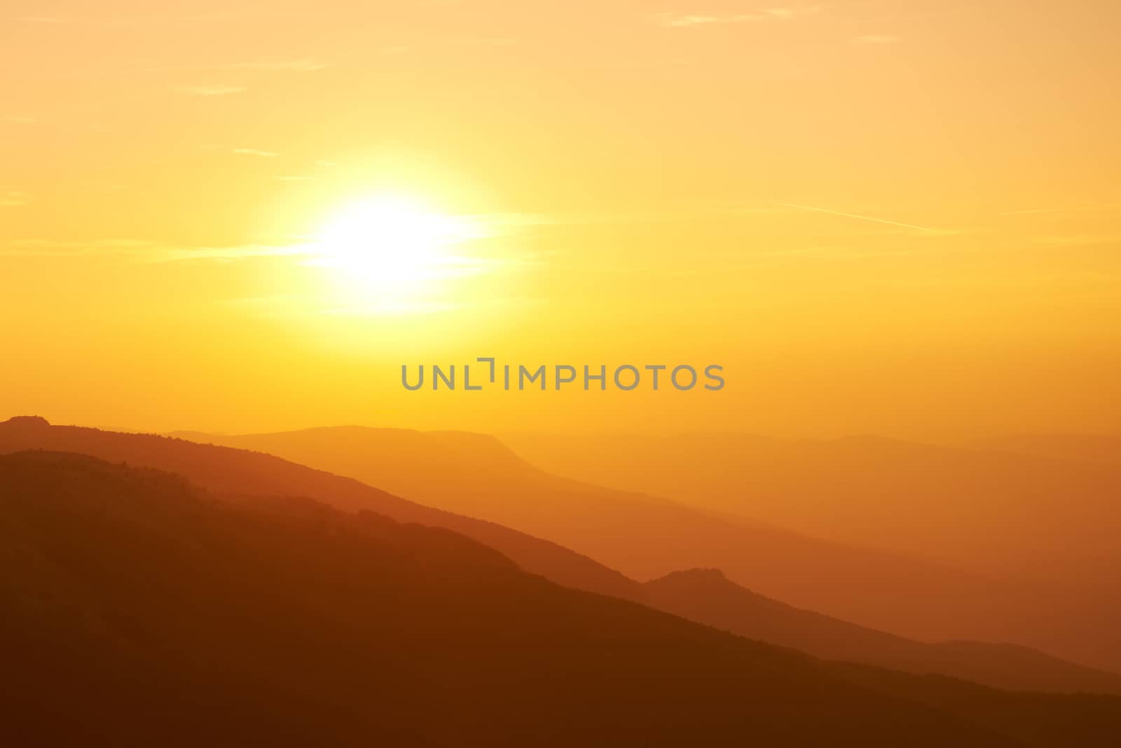 Beautiful sunset at the mountains. Colorful landscape with sun and orange sky