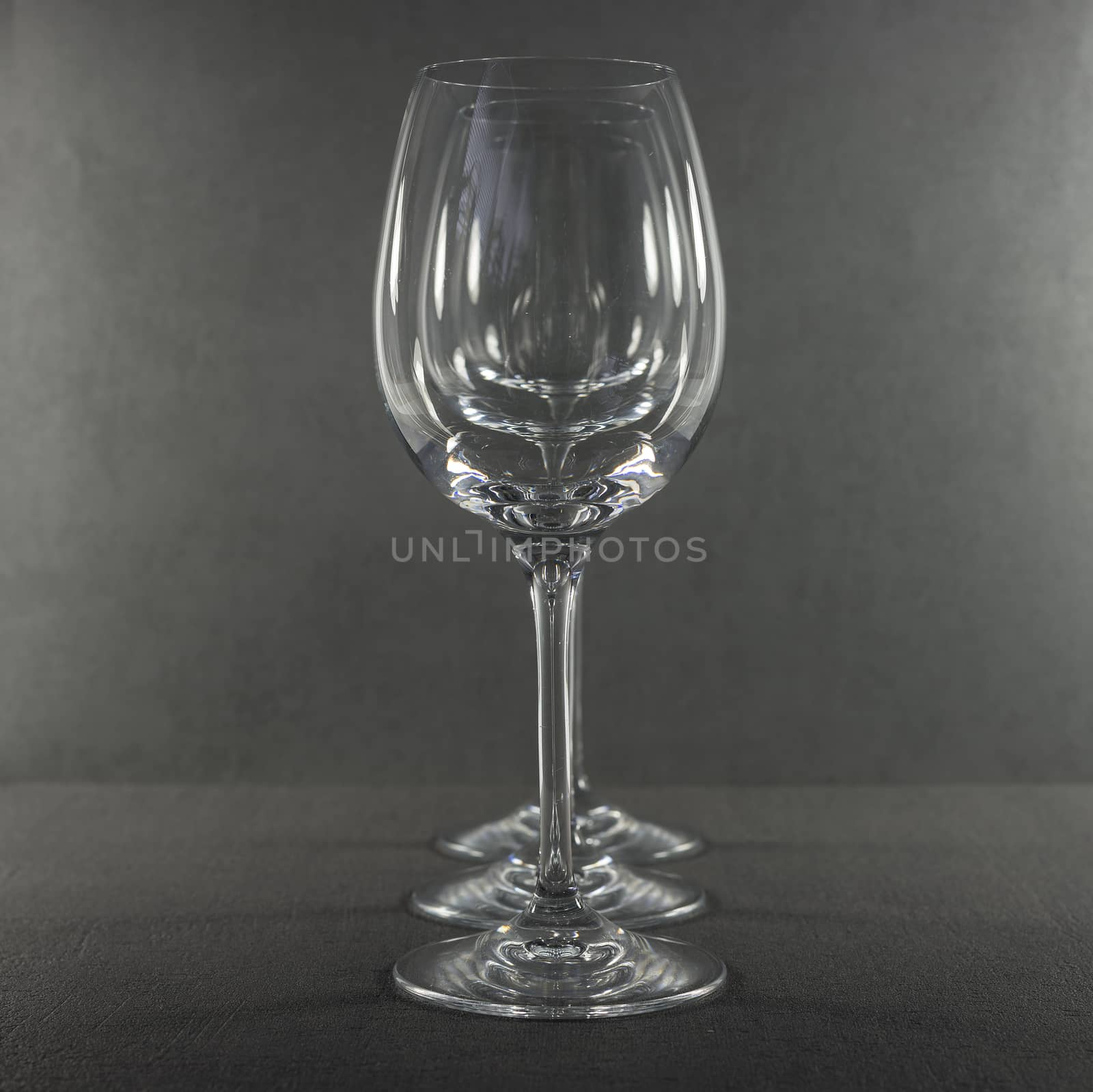 three empty red wine glasses one behind the other in a row
