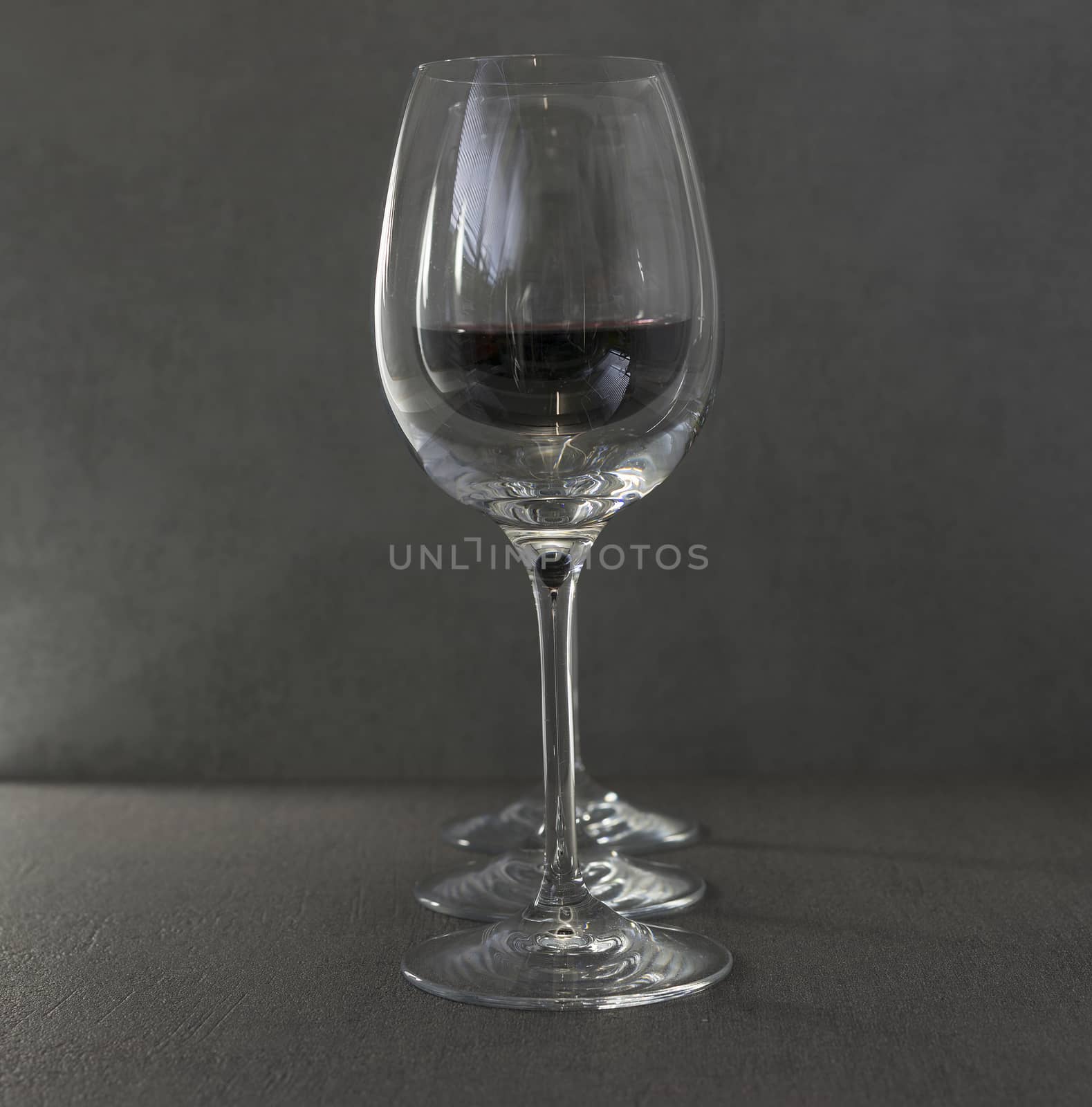 three wine glasses with red wine on dark gray background